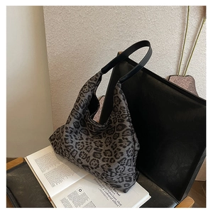 Detail of grey leopard print fabric hobo bag with sleek black leather shoulder strap