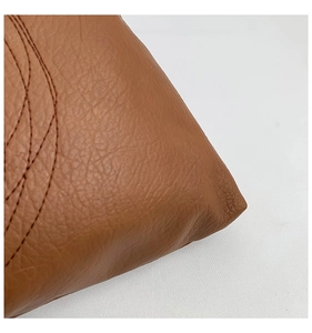 Macro shot of premium brown pebbled leather texture with precise stitching and logo detail