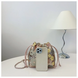 Dettaglio della borsa a secchiello con paillettes e fiori con smartphone per dimensioni