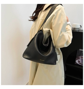 Detail of black pebbled leather hobo tote bag with wide shoulder strap on model