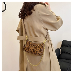 Detailed view of leopard print baguette bag with gold chain and brown leather strap