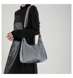 Detail of blue denim hobo bag featuring washed texture and adjustable long shoulder strap