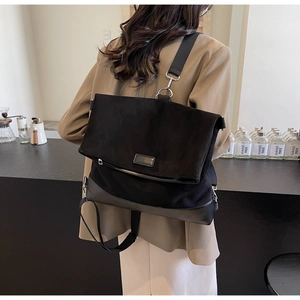 Close-up of black oversized suede backpack with wide nylon strap and metal buckle detail