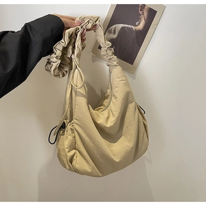 Detail van beige wolktas met geplooide trekkoordtextuur en brede schouderriem