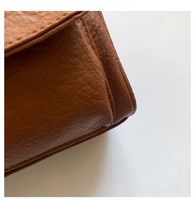 Detail of brown lychee grain leather corner and precision stitching on shoulder bag