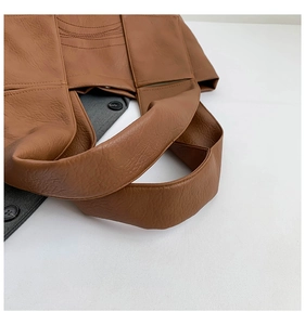 Detail shot of brown lychee grain leather tote with wide strap and decorative stitching