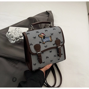 Detail of retro houndstooth handbag with leather trim and dachshund puppy embroidery