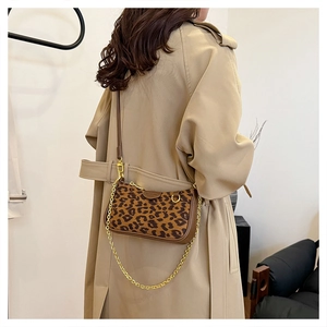 Detailed close-up of leopard print baguette bag with golden chain strap and leather trim