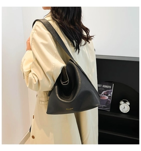 Detail of a matte black leather bucket bag with a folded structure and wide shoulder strap