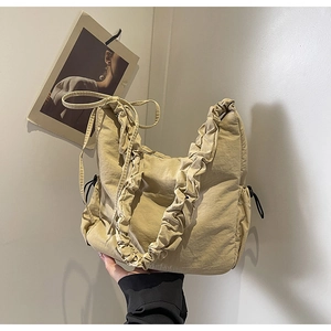 Detail van de beige geplooide cloud bag met trekkoorden en gegolfde schouderband