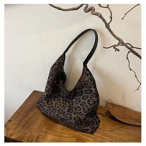Detail of grey leopard print hobo bag with wide black leather strap on a wooden surface