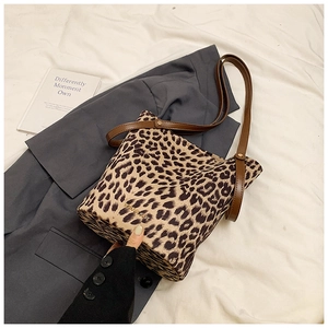 Close-up of leopard print bucket bag featuring brown leather strap and gold logo detail