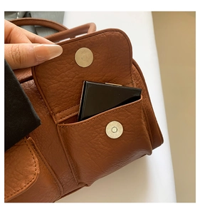 Close-up of brown leather bag with functional front pocket and magnetic closure detail