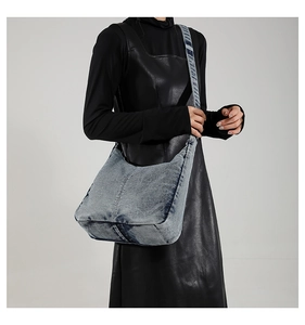 Detailed view of vintage washed blue denim hobo bag worn as a shoulder bag on a model
