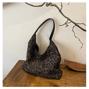 Macro detail of leopard print tote bag texture and black shoulder strap on wooden desk