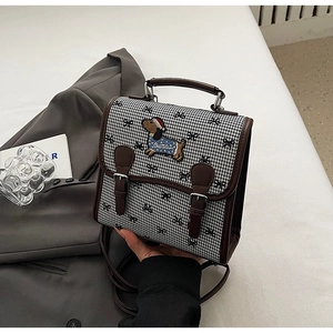 Detail of retro houndstooth backpack with dog embroidery and brown leather straps