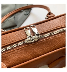 Close-up of brown litchi pattern leather bag with premium silver dual zipper closure