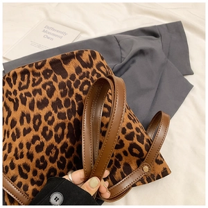 Detailed close-up of leopard print tote bag with brown leather handles and metal rivets