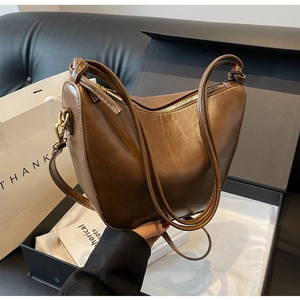Close-up of brown vintage leather hobo bag with sleek zipper and gift packaging