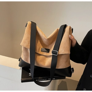 Close-up of camel suede and black leather shoulder bag with wide nylon strap