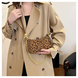 Detail of leopard print baguette bag with gold chain strap on stylish khaki coat