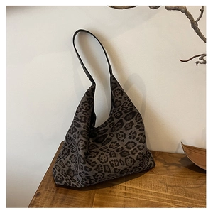 Detailed view of leopard print tote bag on a rustic wood table with natural accessories