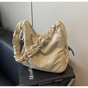 Detailweergave van beige wolkentas met geplooide nylon textuur en accenten van trekkoord