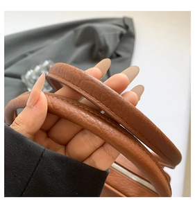 Detailed macro view of the brown leather texture and stitching on the handbag handle