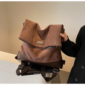 Detail of dark coffee suede tote bag with metallic plaque and reinforced leather corners