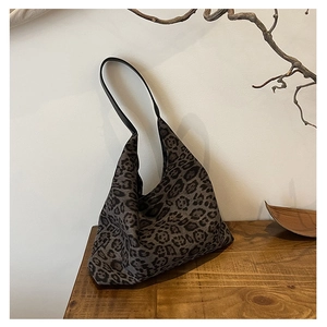 Detail view of large leopard print tote bag on a wooden table with artistic backdrop
