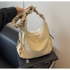 Detail van beige halve maan tas met trekkoord en gerimpelde band op zwart leer
