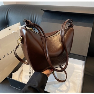 Detail of dark brown hobo bag featuring glossy finish and elegant knotted shoulder strap