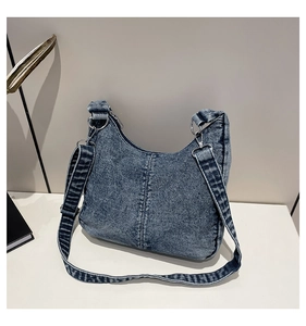 Detail view of washed blue denim hobo bag featuring silver ring buckle and decorative stitching