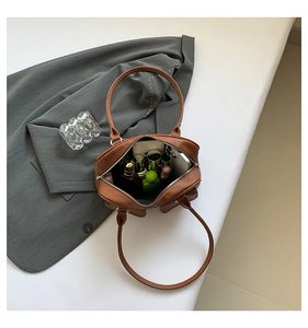 Interior view of brown leather shoulder bag showing storage for phone and cosmetics