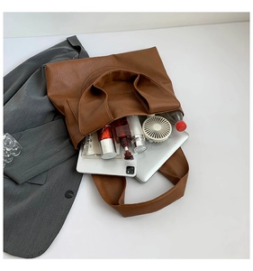 Top view of large brown tote bag showing spacious interior with laptop and cosmetics