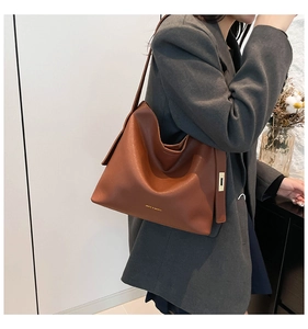 Detail of caramel brown matte leather tote bag with gold metal buckle and brand logo