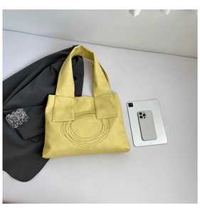 Detail of yellow pebbled leather tote bag featuring circular stitching for business style