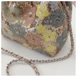 Dettaglio del ricamo con paillettes floreali e tracolla a catena in metallo intrecciato