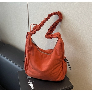 Detail van een oranje geplooide wolktas met trekkoordzakken en een scrunchie-schouderriem