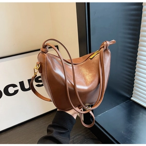 Detail of soft brown leather bucket bag showing knotted shoulder strap and gold hardware