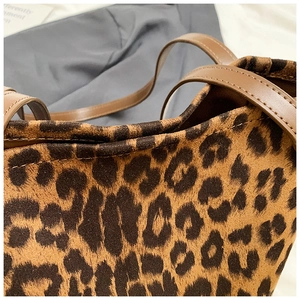 Detailed view of leopard print faux suede tote bag with brown leather handles and stitching