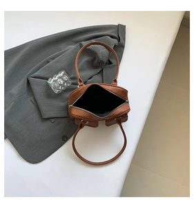 Detail view of brown leather underarm bag interior showing black lining and dual front pockets