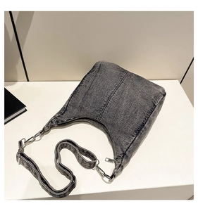 Detailed close-up of a grey denim crescent moon shoulder bag with silver hardware