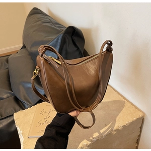Detail of vintage brown crescent bag showing soft leather texture and golden metal hooks