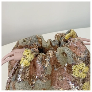 Dettaglio borsa a secchiello con paillettes floreali, coulisse rosa e tracolla a catena