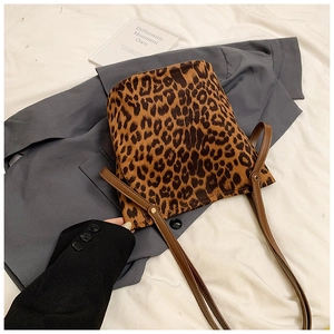 Detail of leopard print tote bag with brown leather strap and metal rivet reinforcement