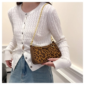 Chic leopard print baguette bag with gold chain strap on model with white knit cardigan