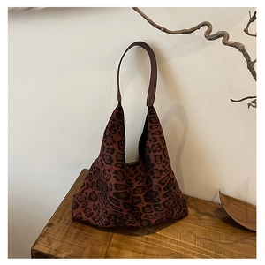 Detailed close-up of dark reddish leopard print hobo bag with wide leather shoulder strap