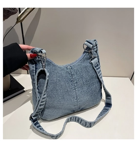 Close-up of blue denim crescent bag showing detailed stitching and metal buckle