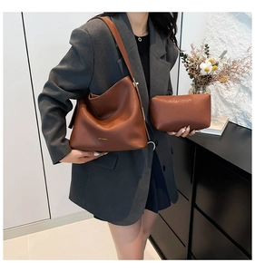 Detail view of brown leather bucket bag set with matching pouch and minimalist gold logo